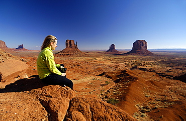 Young woman sitting on a rock looking at the view, Monument Valley, Utah, North America, America