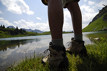 View at the legs of a hiker in front of a mountain lake, Allgaeu Alps, Bavaria, Germany, Europe