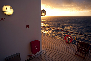 Promenade deck with clock, life buoy and deck chair, sunset, Cruise liner Queen Mary 2, Transatlantic, Atlantic ocean