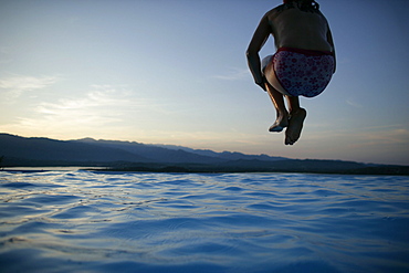 Girl jumping into pool, sunset, bay of Porto Vecchio, Southern Corse, France