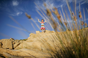 Girl standing on large rocks, Liamone Beach, Western Corse, France