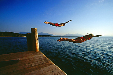 Man and women jumping in lake, Chieming, Chiemsee, Upper Bavaria