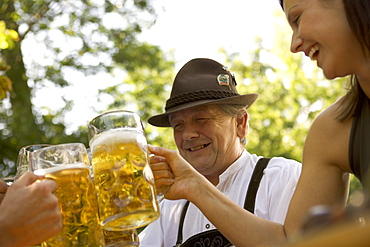 Older Bavarian man and young woman toasting each other, Munich, Bavaria