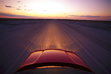 View at the bonnet of a BMW on a dirt road at sunset, Namibia, Africa