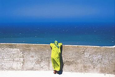 Woman leaning on a wall looking at the sea, Medina, Tanger, Morocco, Africa