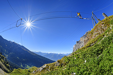 Woman on the Gemmi adventure via ferrata goes over rope bridge, Valais Alps in the background, Gemmi, Bernese Alps, Valais, Switzerland