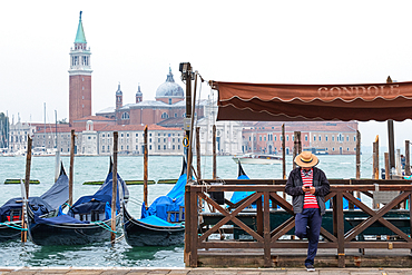 View of the Venetian gondolas and a gondolier on St. Mark's Square, in the background the island of San Giorgio, Venice, Veneto, Italy, Europe