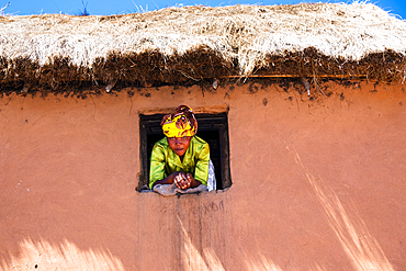 Woman looks out of the window, village in the highlands of Madagascar, Africa