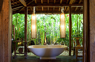 Freestanding bathtub inside an open bathroom in an old wooden house in Bali. Bali, Indonesia.