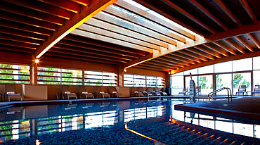 Indoor pool, with rooftop lighting and large windows illuminating the wooden structure, Madrid, Spain.