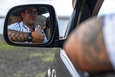 Thumbs up: a man with tattoos on his arm looks in the rearview mirror of his four-wheel drive vehicle, Tekoapa, Ua Huka, Marquesas Islands, French Polynesia, South Pacific