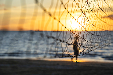 Detail of volleyball net with silhouette of man running on the beach at Pullman Nadi Bay Resort