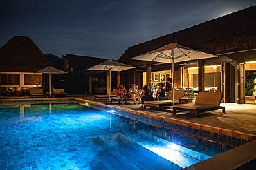 People relaxing by the private swimming pool of a residence villa accommodation at Six Senses Fiji Resort at night, Malolo Island, Mamanuca Group, Fiji Islands, South Pacific