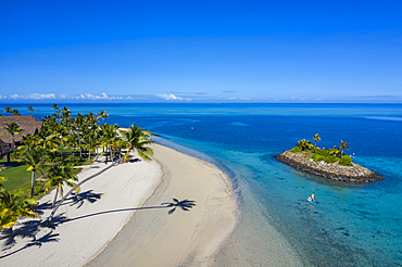 Aerial view of a Residence Villa accommodation in the Six Senses Fiji Resort with coconut trees, a beach and a family enjoying water sports activities next to a small offshore island, Malolo Island, Mamanuca Group, Fiji Islands, South Pacific