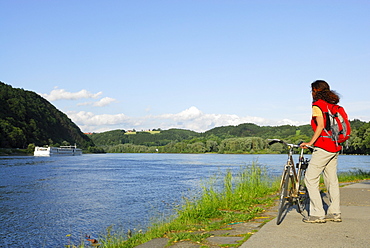 Female cyclist looking over river Danube, Danube Cycle Route Passau to Vienna, Passau, Lower Bavaria, Germany