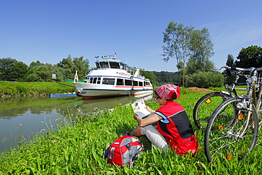 Woman sitting in meadow near river Danube while reading, Ardagger Markt, Lower Austria, Austria