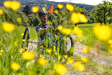 Man rides a bicycle for paraplegics on a dirt road through lush spring meadow, Heimbuchenthal, Räuberland, Spessart-Mainland, Franconia, Bavaria, Germany, Europe