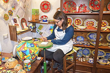 A craftswoman hand painting traditional ceramics, Erice, Sicily, Italy