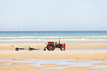 Tractor on the beach with trailer for kite buggies- Omaha Beach, Calvados, France.