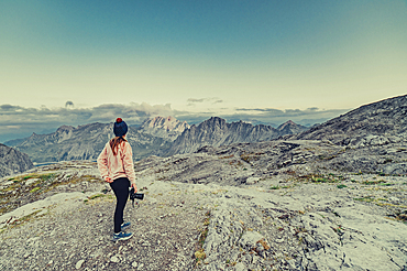 Woman with camera stands on a mountain near Lünersee, Vorarlberg, Austria, Europe