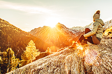 Woman sits on rocks in Maloja and enjoys the sunset, Engadin, Graubünden, Switzerland, Europe