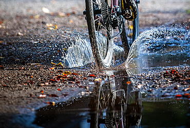 Autumn weather, Gravel biker drives through puddle