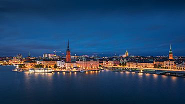 Illuminated skyline of Stockholm at night with Riddarholmskyrkan church on Gamla Stan old town island in Sweden