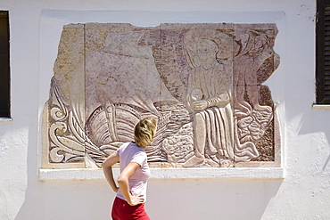 Young women looking at the stone mural of Henry the Navigator (15th century), MR, West coast of Algarve, Sagres, Algarve, Portugal