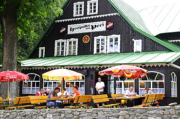 People sitting in front of the Inn na Pezi at the village Pec, Bohemian mountains, east-bohemian, Czech Republic, Europe