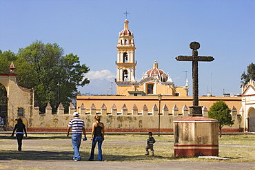 Family walking over the grounds of Ex-convento de San Gabriel in Cholula, the church of San Pedro is in the background, State of Puebla, Mexico