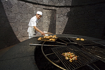 Cook cooking food on a volcanic grill, volcanic heat, Timanfaya Restaurant, architect Cesar Manrique, Parque Nacional de Tiimanfaya, Montanas del Fuego, Lanzarote, Canary Islands, Spain, Europe