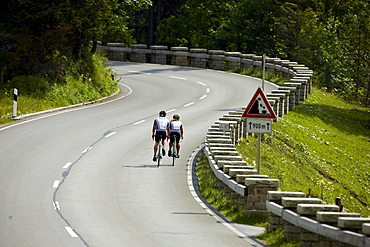 Two racing cyclists on bendy road, Spitzing, Bavaria, Germany