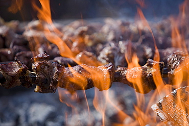 Grilling Espetada beef skewer kebabs over an open fire at a religiois festival, Ponta Delgada, Madeira, Portugal