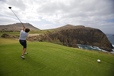 Golfer tees off at hole 14 at Porto Santo Golfe Golf Course, Porto Santo, near Madeira, Portugal