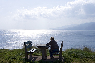 Woman sitting at a picnic table near Ponta de Sao Laurenco enjoying the view, Near Canical, Madeira, Portugal