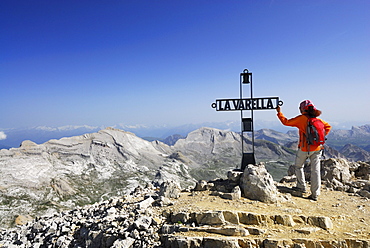 Woman summit cross of La Varella, Zehner and Neuner in background, Naturpark Fanes-Sennes-Prags, Dolomites, Trentino-Alto Adige/South Tyrol, Italy