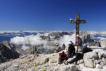 Group of mountaineers resting at summit cross of mount Kesselkogel, Rosengarten group, Dolomites, Trentino-Alto Adige/South Tyrol, Italy