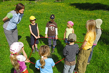 Children standing in a ring on a meadow, woman giving instructions, Bavarian Alps, Upper Bavaria, Bavaria, Germany