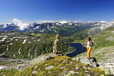 Woman near cairn above reservoir Lago della Sella, Gotthard range, Canton of Ticino, Switzerland