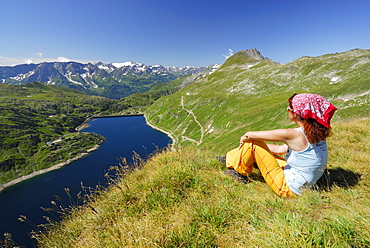 Woman looking over reservoir Lago della Sella to Ticino Alps, Gotthard range, Canton of Ticino, Switzerland