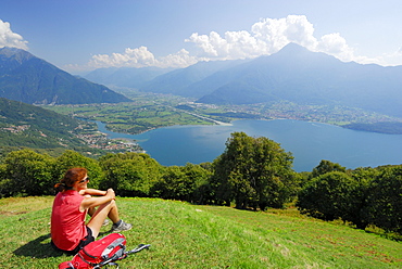 Woman sitting on meadow and looking over Lake Como, Monti Lariani, Lombardy, Italy