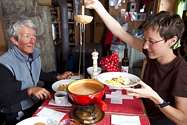 Two women enjoying tomato fondue, mountain lodge Cabane de l'A Neuve, Val Ferret, Canton of Valais, Switzerland