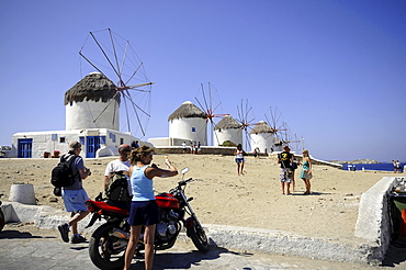 People and windmills at Venetia quarter under blue sky, island of Mykonos, the Cyclades, Greece, Europe