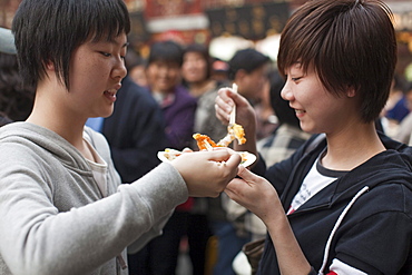 Two young women eating outside the Huxinting Teahouse, Yu Yuan Garden, Nanshi, Feng Shui, Shanghai, China, Asia