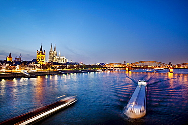 View over river Rhine to old town with cathedral and Great St. Martin church at night, Cologne, North Rhine-Westphalia, Germany