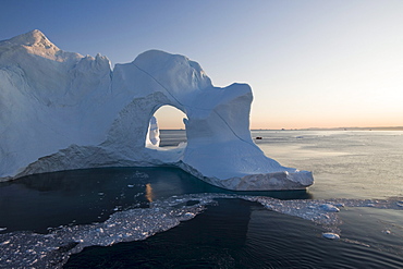 View at iceberg with hole at Ilulissat Kangerlua Isfjord at dusk, Disko bay, Kitaa, Greenland