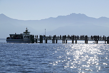 Ferryboat at the main pier, Kampenwand Mountain in the background, Fraueninsel, Lake Chiemsee, Chiemgau, Bavaria, Germany