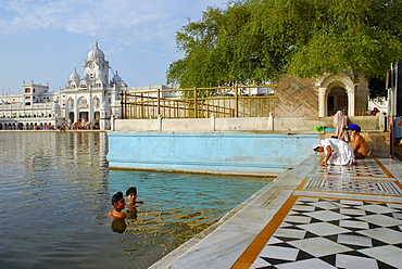 Golden Temple, two young Sikh men bathing in the holy lake, Sikh holy place, Amritsar, Punjab, India, Asia