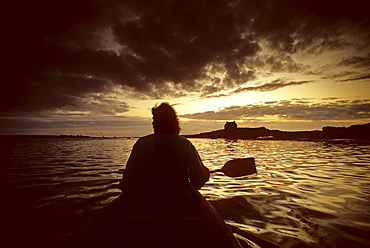 Angler in rowing boat off the coast at sunset, Brittany, France, Europe