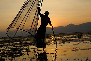 Intha fisherman on his fishing boat on Inle Lake at sunset, Shan State, Myanmar, Burma